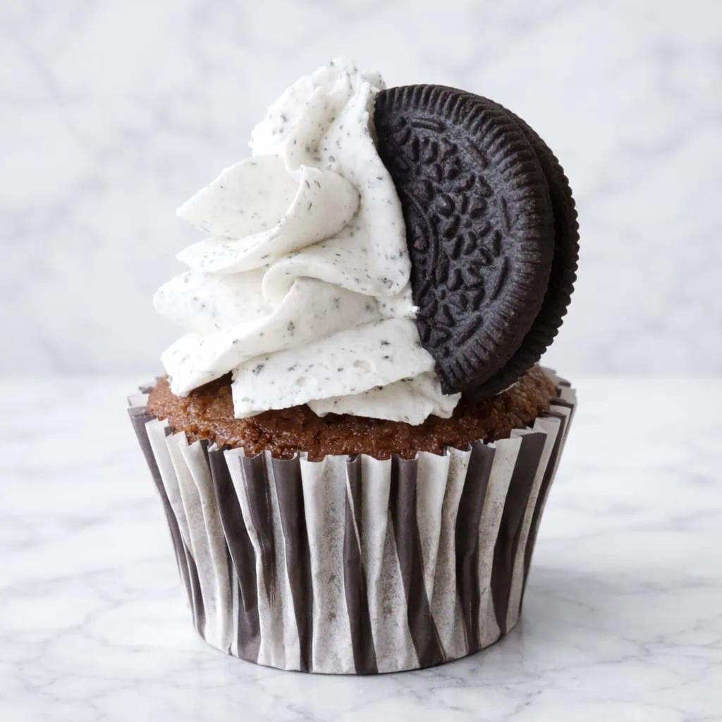 Cookies and cream cupcake with vanilla, Oreo pieces, and topped with an Oreo.