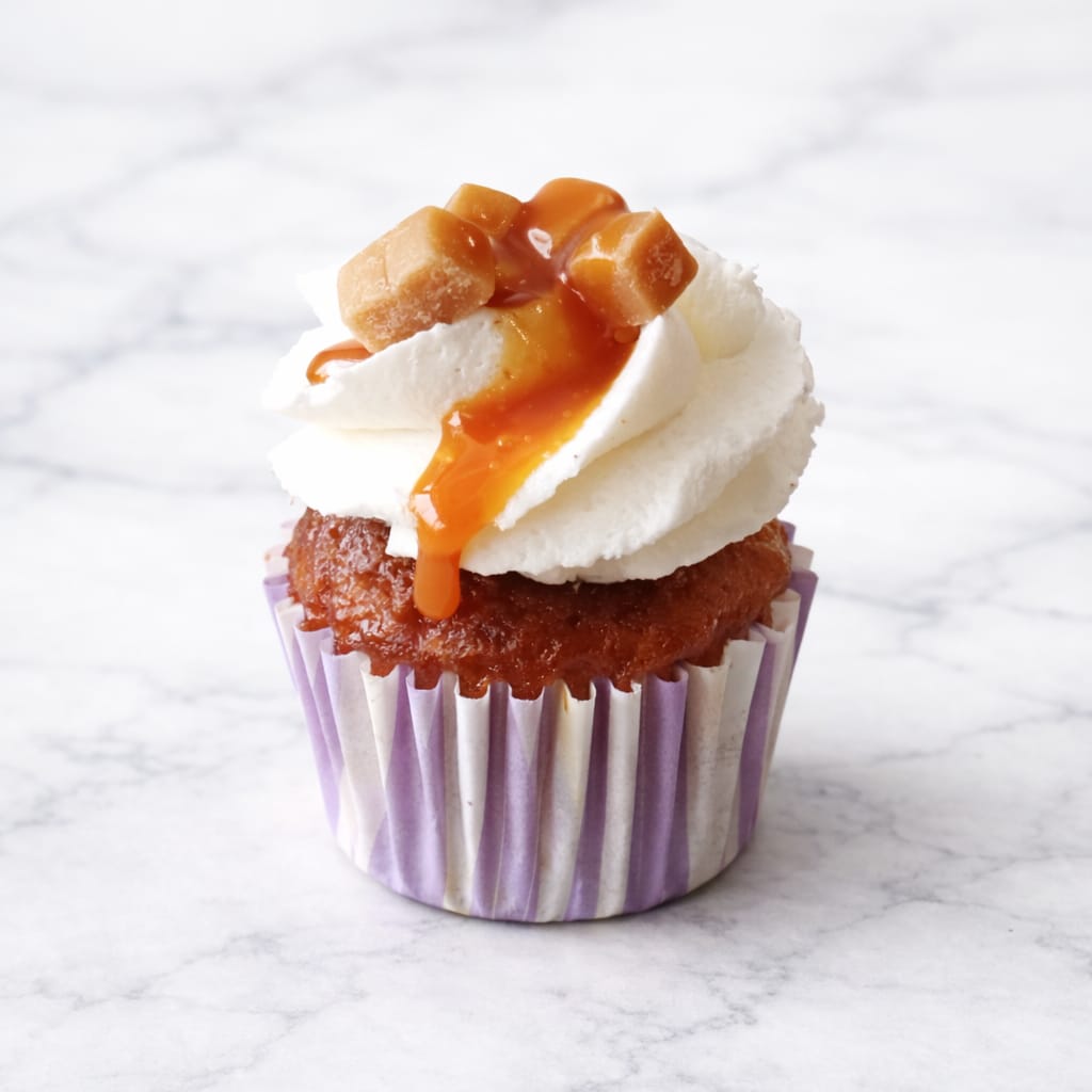 Mini salted caramel cupcake with caramel drizzle and mini caramel cubes.