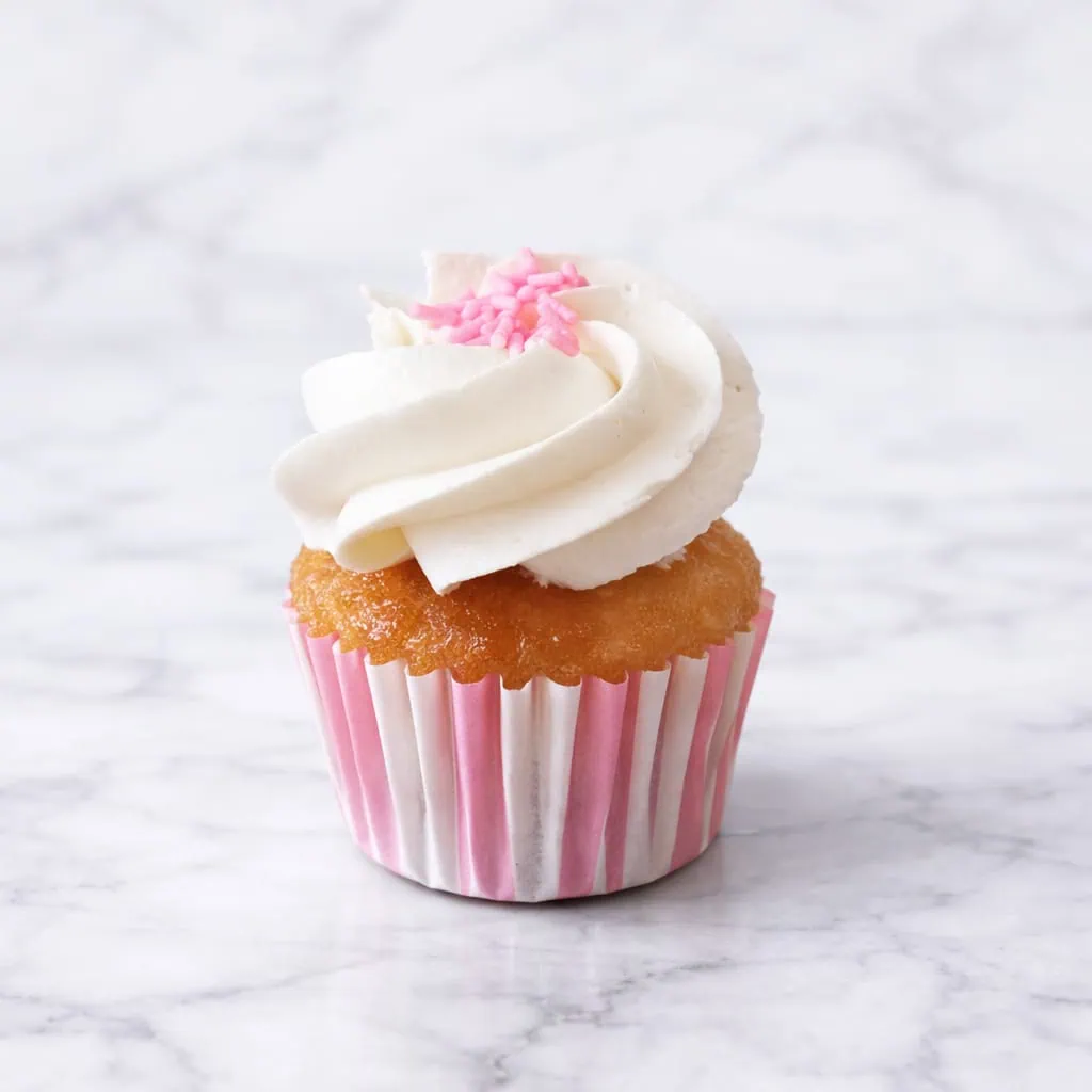 Delicious vegan mini vanilla cupcake on a festive backdrop.