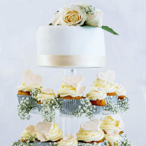 Elegant classic wedding cake with smooth fondant icing and matching cupcakes featuring bride and groom's initials