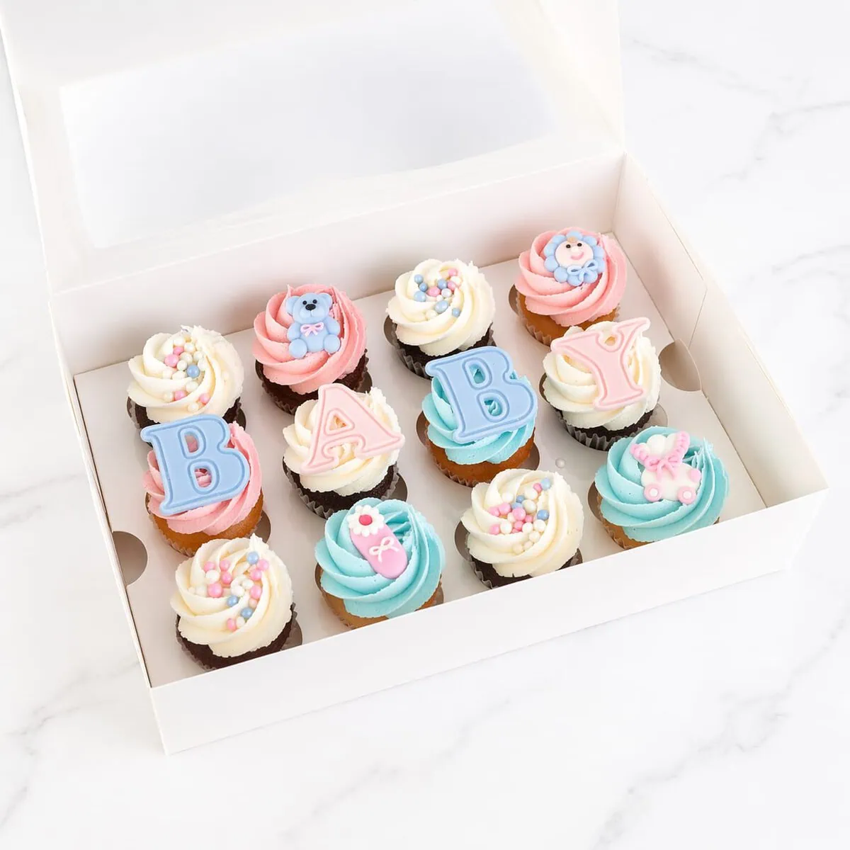 Baby Shower cupcake box with assorted baby shower cupcakes in blue and white for boys, pink and white for girls, and mixed colors for any baby, decorated with créme and baby sugar decorations