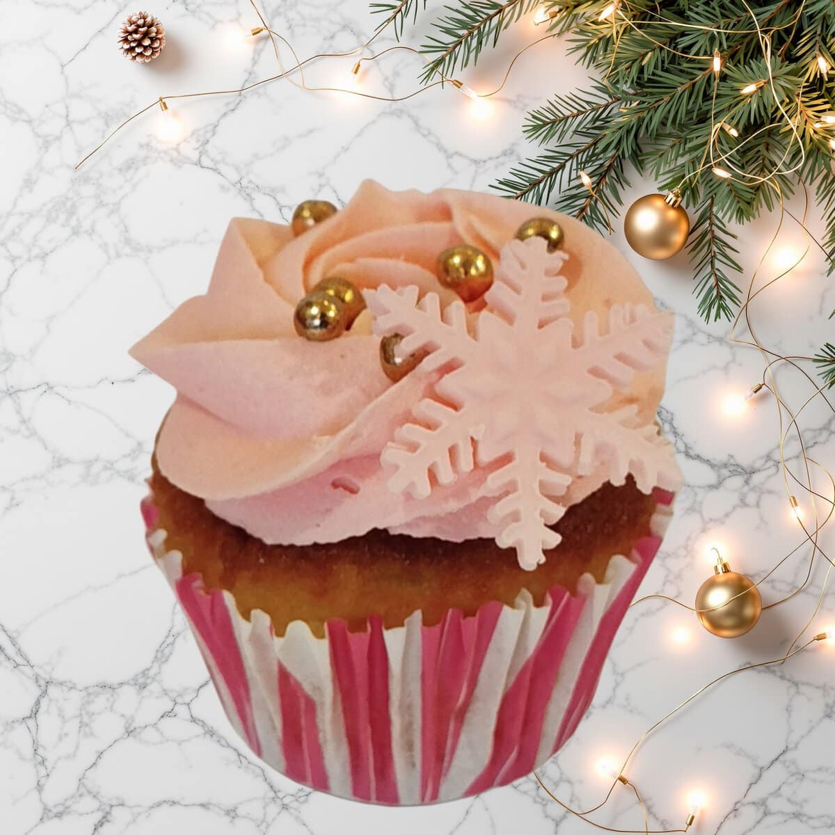 Christmas Vanilla Cupcake with pink fondant snowflake and festive decorations.