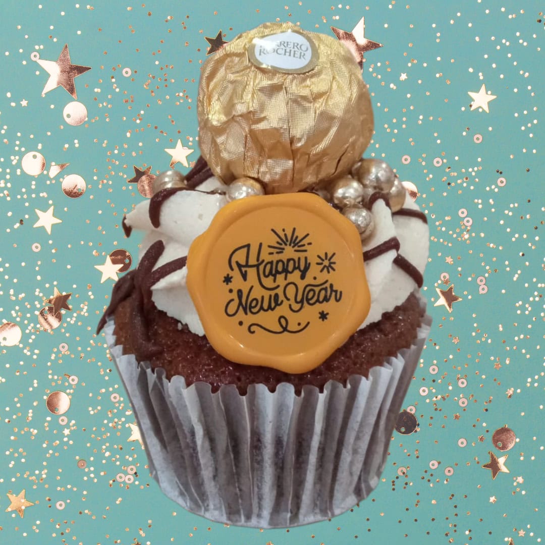 A decadent chocolate and hazelnut cupcake topped with a gold Ferrero Rocher chocolate and gold "Happy New Year" decorations.