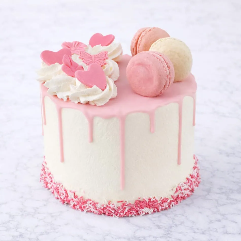Macaron drip cake with pink chocolate and macaron toppings.