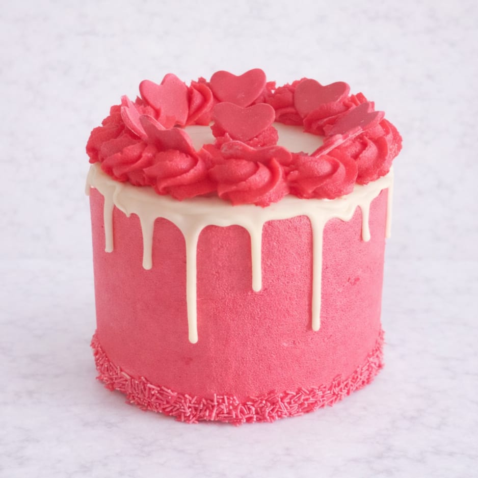 Queen of Hearts Red Velvet Drip Cake with cream cheese frosting, white chocolate drip, and red fondant hearts on a 15 cm cake